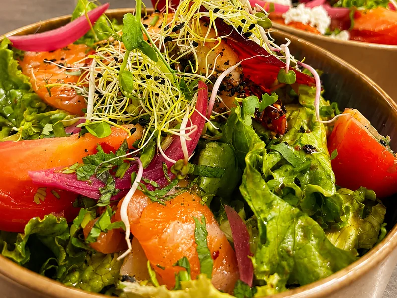 Salade de saumon fumé, tomate et oignon rouge, servie en coupelle dorée